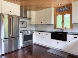 Kitchen in new log cabin home, with white cabinetry and black soapstone countertops.